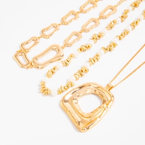 Detailansicht der mehrlagigen goldenen Halsketten mit unregelmäßigen Perlen und Anhängern