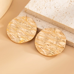 Macro detail of U-shaped gold earrings with water ripple texture and hammered finish