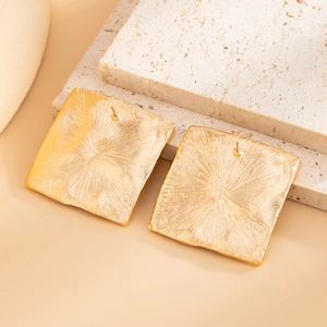 Macro detail of square gold studs with sunburst texture on a natural stone base