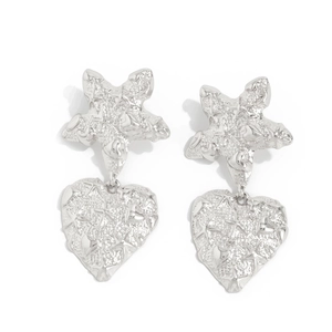 Detailed macro view of silver star and heart earrings with embossed metal texture
