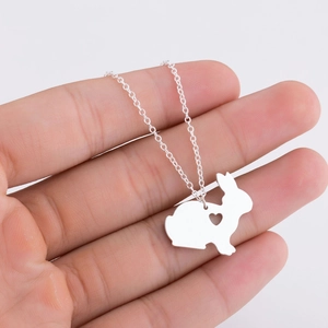 Minimalist silver rabbit necklace with hollow heart pendant shown on hand close-up
