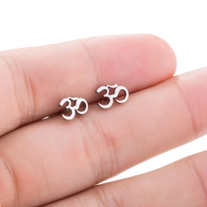 Primer plano de pendientes de plata con símbolo Om sostenidos en la mano para escala