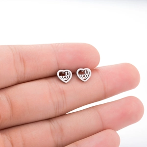 Detail view of silver hollow heart-shaped stainless steel earrings on a finger