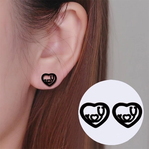 Close-up of black heart stethoscope stud earrings on ear showing delicate medical design