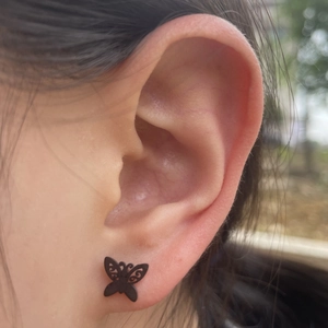 Minimalist black hollow butterfly stud earrings on female model in a stylish close-up
