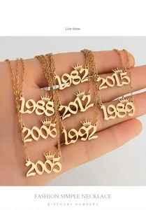 Detailweergave van gouden kroon jaar kettingen in de hand voor maatvergelijking