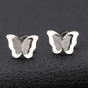 Vista macro de pendientes de mariposa con acabado en metal plateado pulido y mate