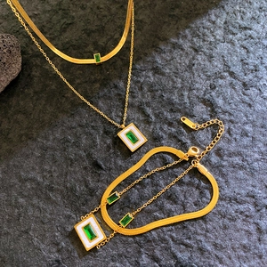Double-layered gold necklace set with green square zircon and white shell on black rock