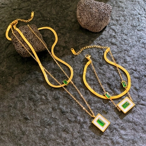 Double-layered golden necklace with white shell square pendant and green stone centerpiece