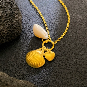 Collana dorata a tema marino con ciondoli a conchiglia e cuore su pietra scura