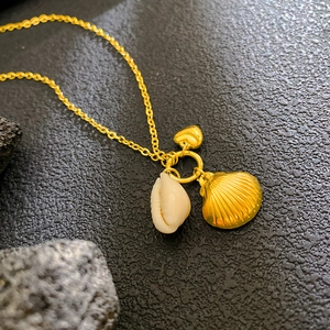 Collana dorata con ciondoli a conchiglia e cuore su una catena chic da donna