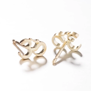 Gros plan de boucles d'oreilles dorées symbole Om avec détails métalliques ajourés précis