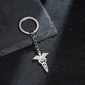 Detailed close-up of a silver medical caduceus pendant on a vintage steel keychain