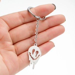 Handgehaltener Schlüsselanhänger aus Edelstahl mit schmelzendem Smiley auf weißem Grund