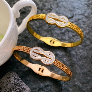 Gold and rose gold Mobius bangles with sparkling zircon crystals on stone background