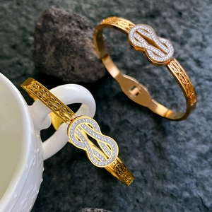 Luxurious gold Mobius knot bangle with sparkling cubic zirconia on a stone background