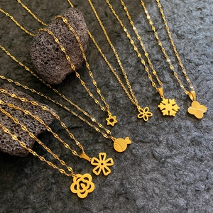 Golden rose and clover pendant necklaces set on dark stone background with volcano rocks