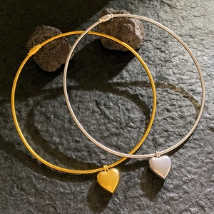Elegante goldene und silberne Herzanhänger-Halsketten auf dunklem Stein mit Magnetverschluss
