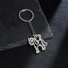 Modern stainless steel unicorn keychain with hollow wing pendant on a stone background
