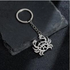Macro detail of the silver crab pendant with geometric hollow design on a stone surface