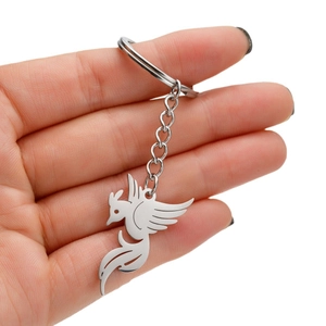 Polished stainless steel phoenix pendant keychain held by hand against a white background