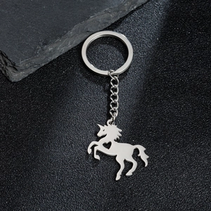 Détail d'un porte-clés licorne argenté avec cœur évidé sur un fond noir texturé