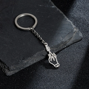 Minimalist silver stainless steel heart hand gesture pendant keychain on stone surface