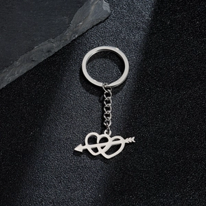 Macro shot of stainless steel interlocking hearts with arrow pendant on black texture