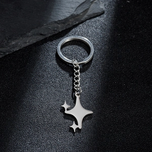 Minimalist silver metal keychain with geometric star charms on a black textured background