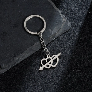 Close-up of polished stainless steel heart and arrow pendant keychain on black stone