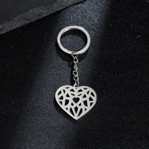 Detailed view of silver heart keychain with hollow geometric patterns on black texture