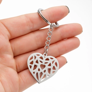 Close-up of hand holding a geometric hollow heart keychain in polished silver steel