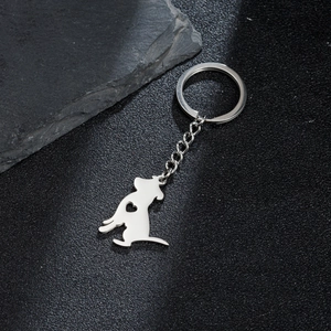 Llavero minimalista de perro en metal plateado con recorte de corazón en fondo oscuro