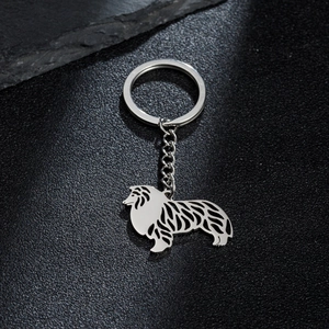 Silver stainless steel cutout dog keychain with collie silhouette on a grey stone background