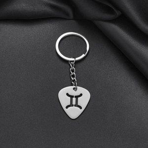 Detailed macro view of a guitar pick shaped Gemini zodiac keychain in silver steel