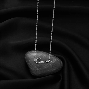 Détail du collier signe du zodiaque Cancer en argent posé sur un galet gris