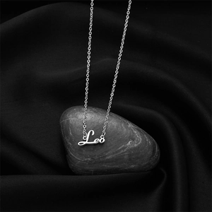Détail macro du collier pendentif prénom Leo en argent sur soie noire et un galet