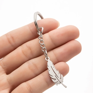 Handheld view of a polished stainless steel feather keychain with shiny metal texture