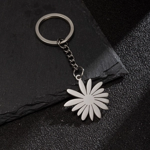 Detailed macro shot of a silver stainless steel daisy flower pendant on a dark stone surface