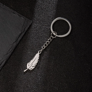 Silver stainless steel keychain featuring a detailed feather pendant on a leather backdrop