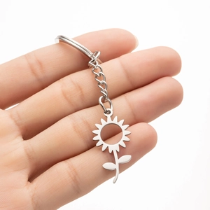 Macro detail of a silver stainless steel sunflower keychain pendant held in hand