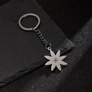 Minimalist silver flower petal keychain with star engraving on stone background