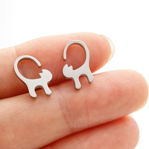 Close-up of minimalist silver cat silhouette stud earrings held on a fingertip
