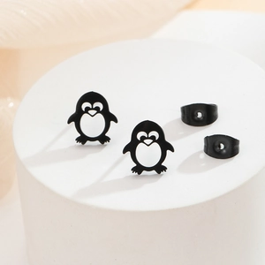 Macro shot of cute black penguin stud earrings with circular hollow design on white stand