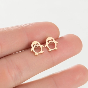 Close-up of cute rose gold penguin stud earrings held to show mini size and scale
