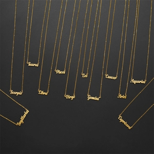 Vista detallada de collares del zodiaco bañados en oro de 18K sobre un fondo negro