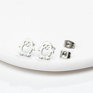 Detailed macro view of penguin earrings with heart cutouts on a minimalist white stand