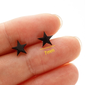 Macro detail of 7mm black minimalist star stud earring on finger showing size and finish