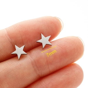 Detail shot of 7mm minimalist stainless steel star studs shown on a fingertip for size
