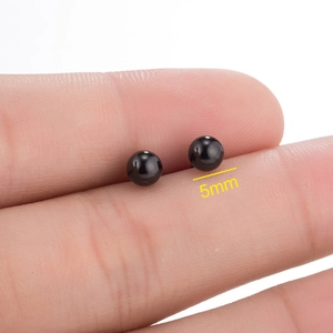 Minimalist 5mm polished black stainless steel ball stud earring held by fingertips